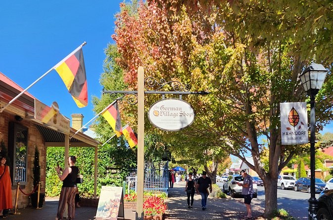 German and Australian flags over a main street lined with autumn trees