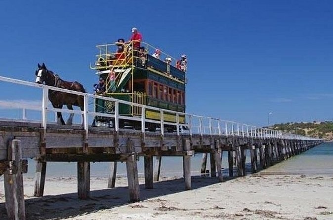 A horse-drawn double-decker tram crossing a long timber causeway
